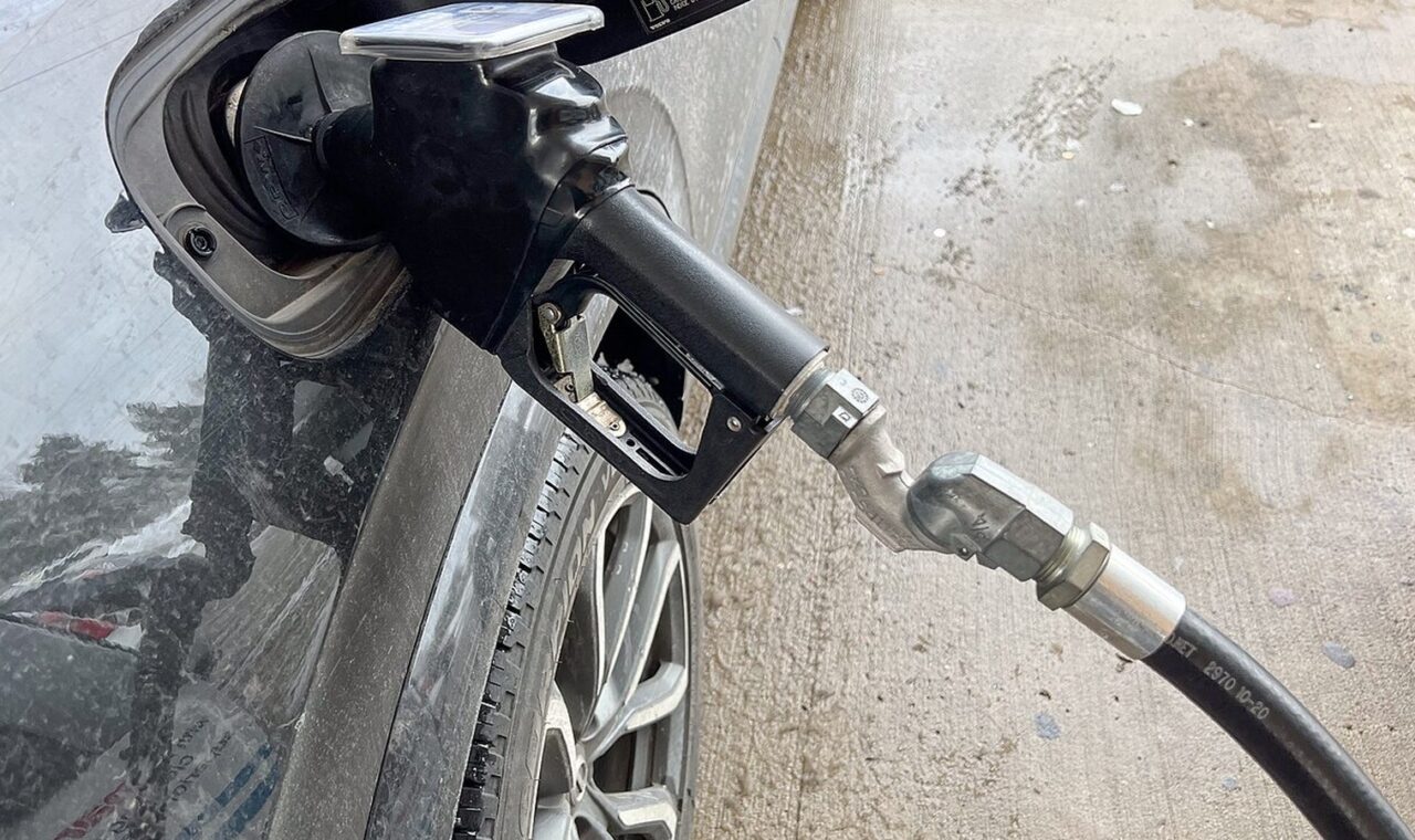 Vozač toči gorivo na benzinskoj pumpi uz prikaz aktualnih cijena goriva.