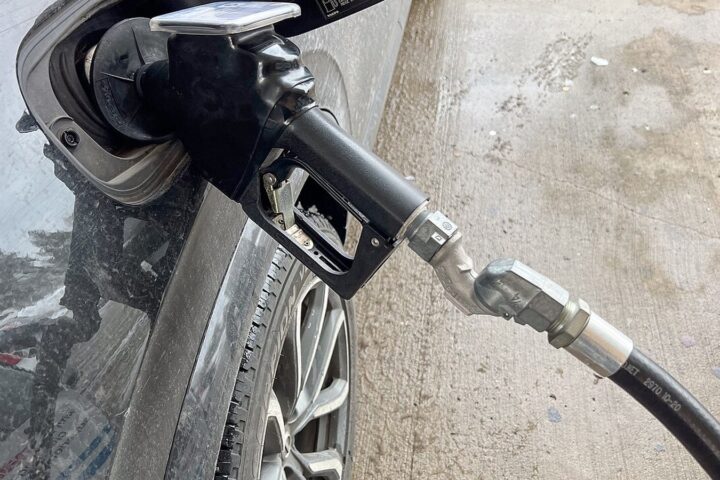Vozač toči gorivo na benzinskoj pumpi uz prikaz aktualnih cijena goriva.