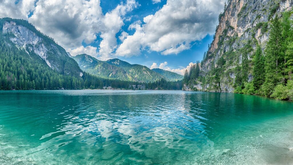 Lago di Braies u Dolomitima s tirkiznom vodom, drvenim čamcima i planinama u pozadini.