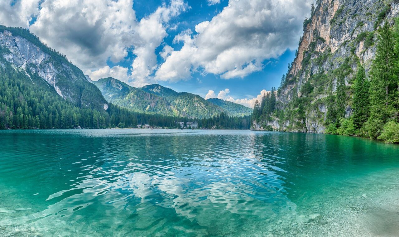 Lago di Braies u Dolomitima s tirkiznom vodom, drvenim čamcima i planinama u pozadini.