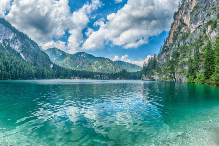 Lago di Braies u Dolomitima s tirkiznom vodom, drvenim čamcima i planinama u pozadini.
