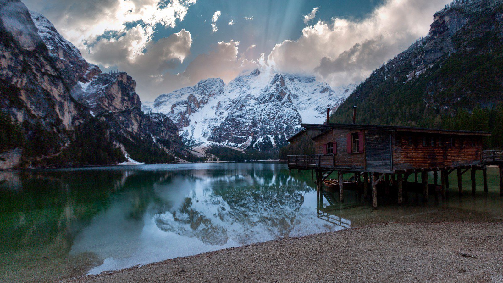 Panoramski pogled na Lago di Braies u Dolomitima, okružen planinama i šumom.
