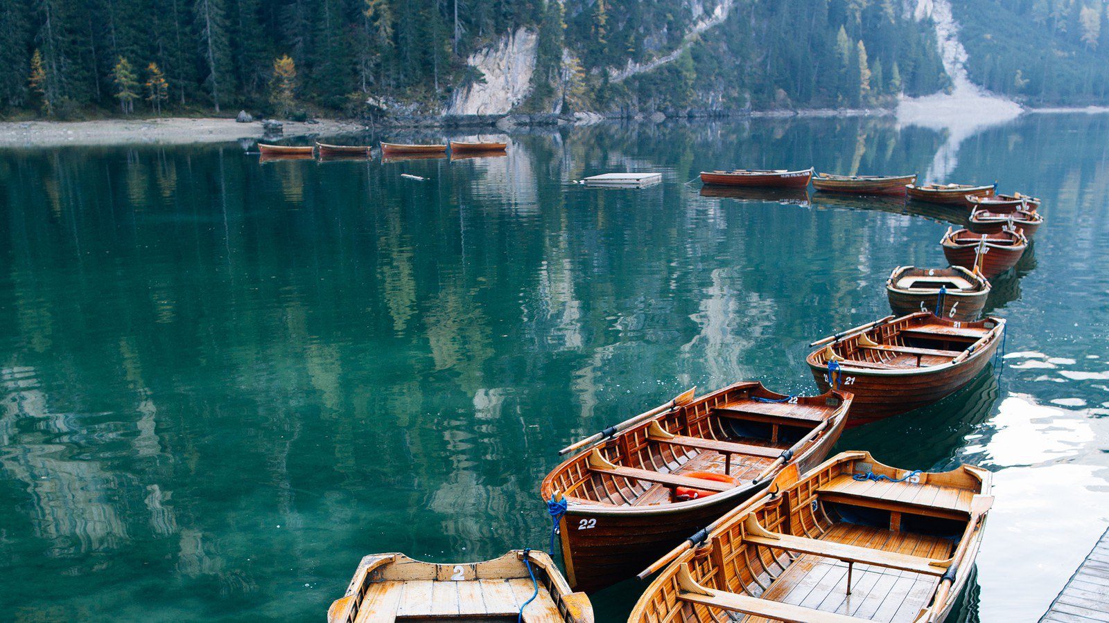 Drveni čamci na Lago di Braiesu s planinama u pozadini.