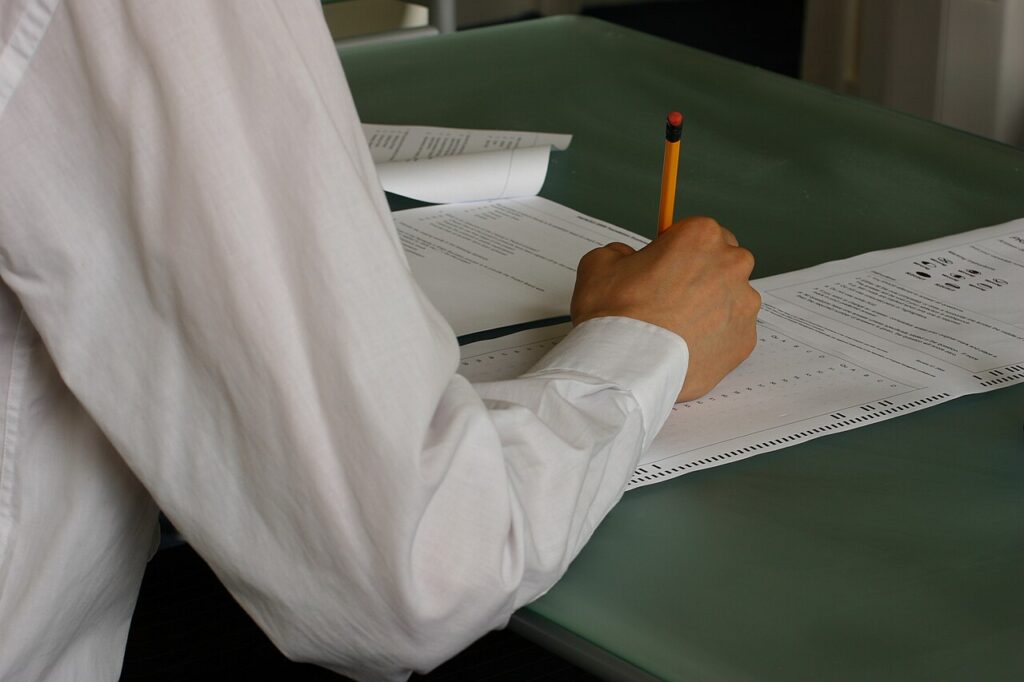 Student writing exam papers in a classroom
