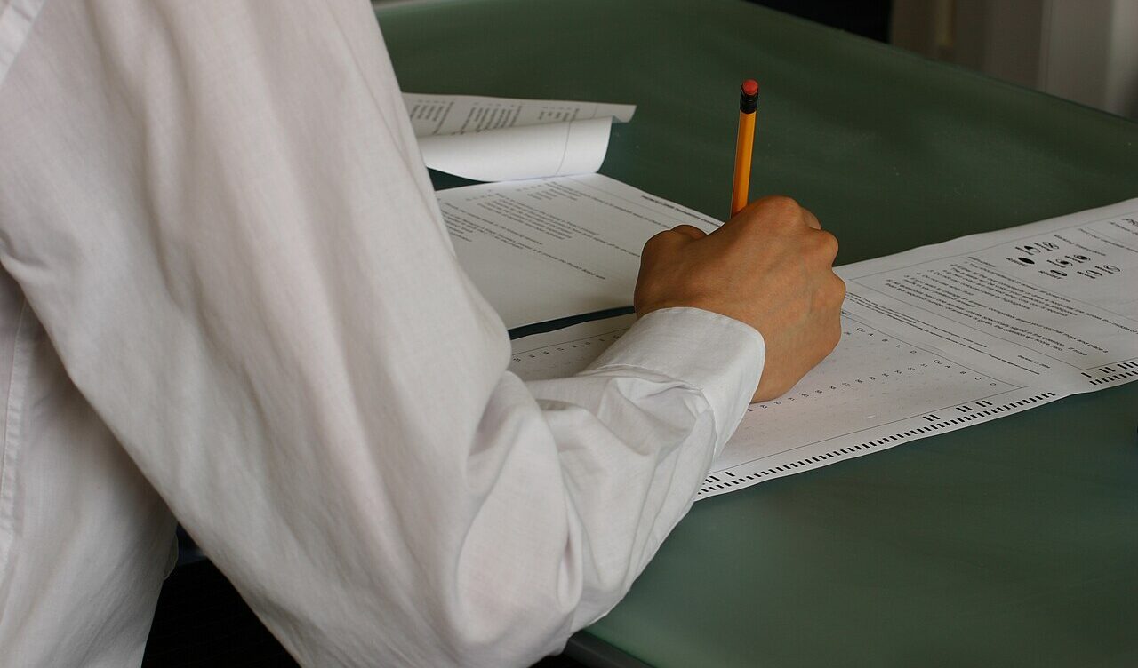 Student writing exam papers in a classroom