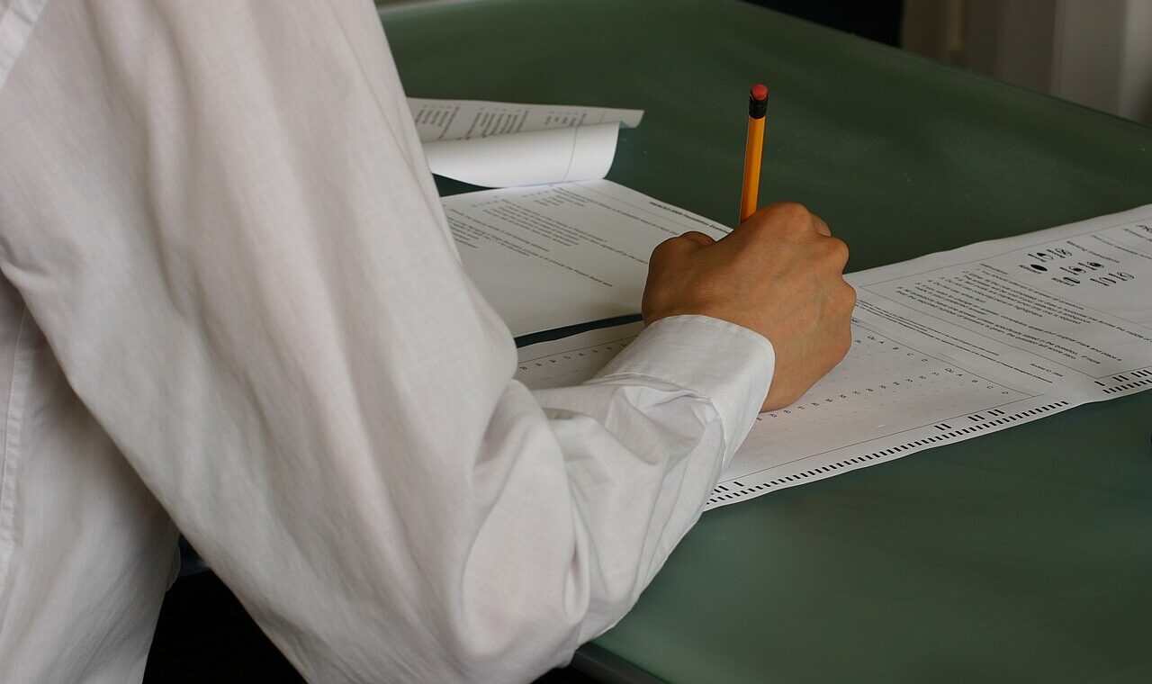 Student writing exam papers in a classroom